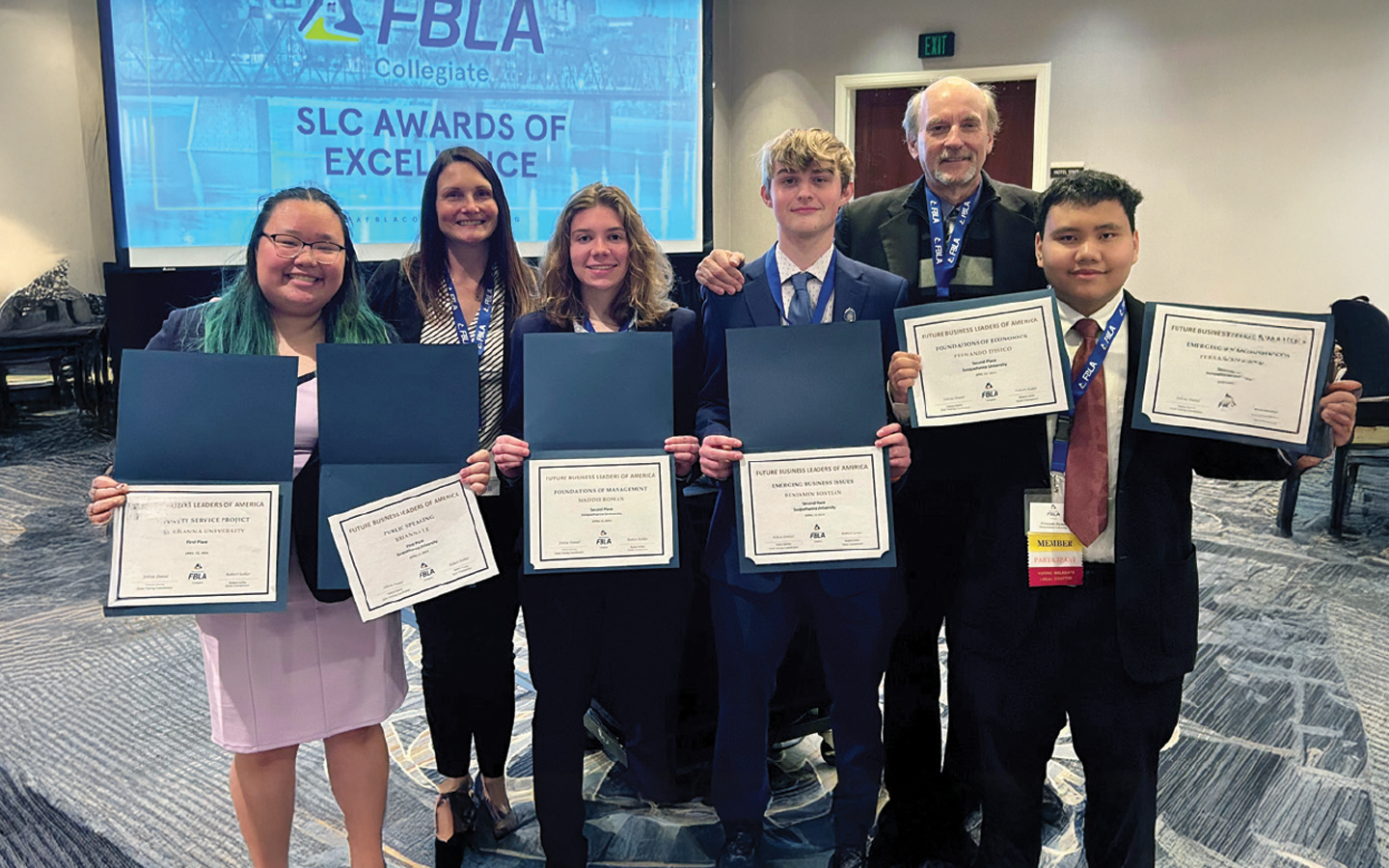 Six individuals standing in a line, each holding certificates, with a banner reading "FBLA SLC Awards of Excellence" in the background.